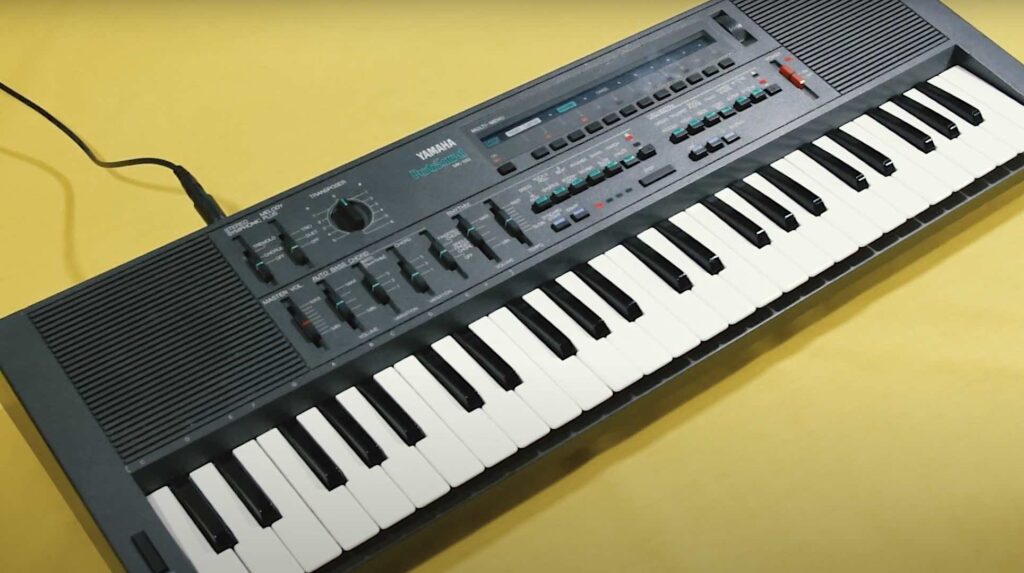 Yamaha MK-100 keyboard against a yellow background