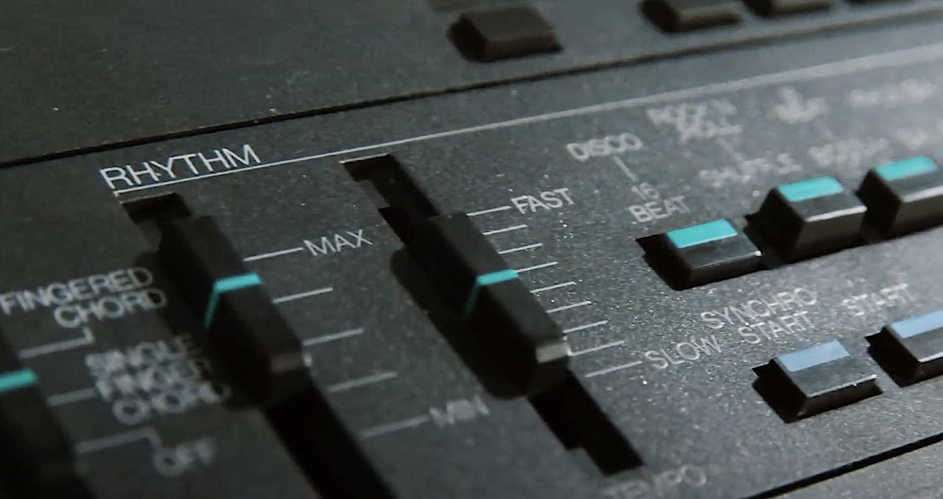 A close-up of buttons and sliders on a Yamaha MK-100 keyboard